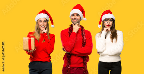 A group of people Blonde woman dressed up for christmas holidays smiling and looking to the front with confident face on yellow background