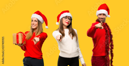 A group of people Blonde woman dressed up for christmas holidays points finger at you with a confident expression on yellow background