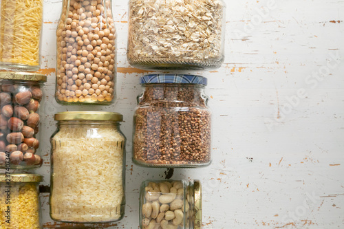 Various uncooked cereals, grains, beans and pasta for healthy cooking in glass jars