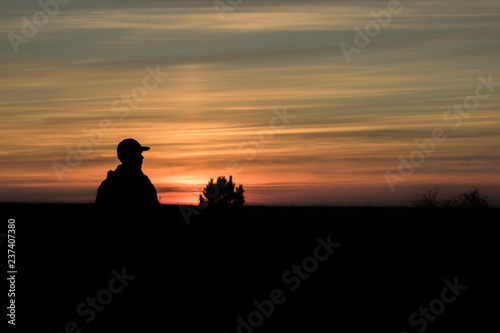 man admiring red autumn sunset in the field  silhouette of man and tree