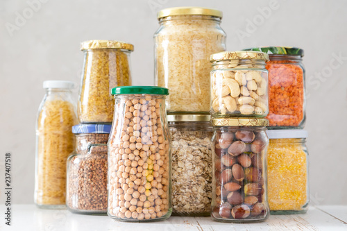 Various uncooked cereals, grains, beans and pasta for healthy cooking in glass jars