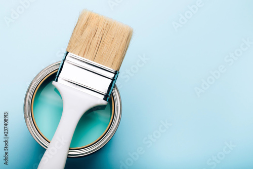 Fototapeta Naklejka Na Ścianę i Meble -  Brush with white handle on open can of turquoise paint on blue pastel background. Renovation concept. Place for text.