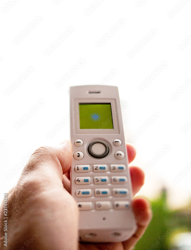 Man hand holding outdoor home office white cordless phone dialing a number on the white keyboard try to reach signal Man hand holding outdoor home office white cordless phone dialing a number on the white keyboard try to reach signal