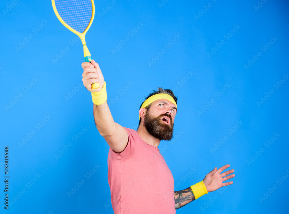 Man bearded hipster wear old school sport outfit with bandages. Tennis  player retro fashion. Athlete hold tennis racket in hand on blue  background. Tennis sport and entertainment. Tennis club concept Stock Photo