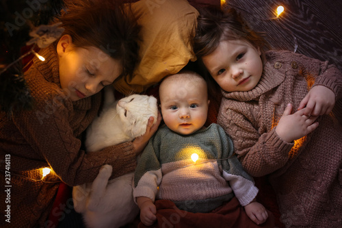 Three children with cat and garland cozy resting