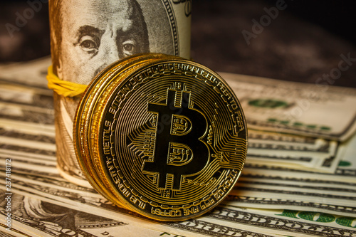 Three coins in the form of bitcoin on a pile of dollars photo