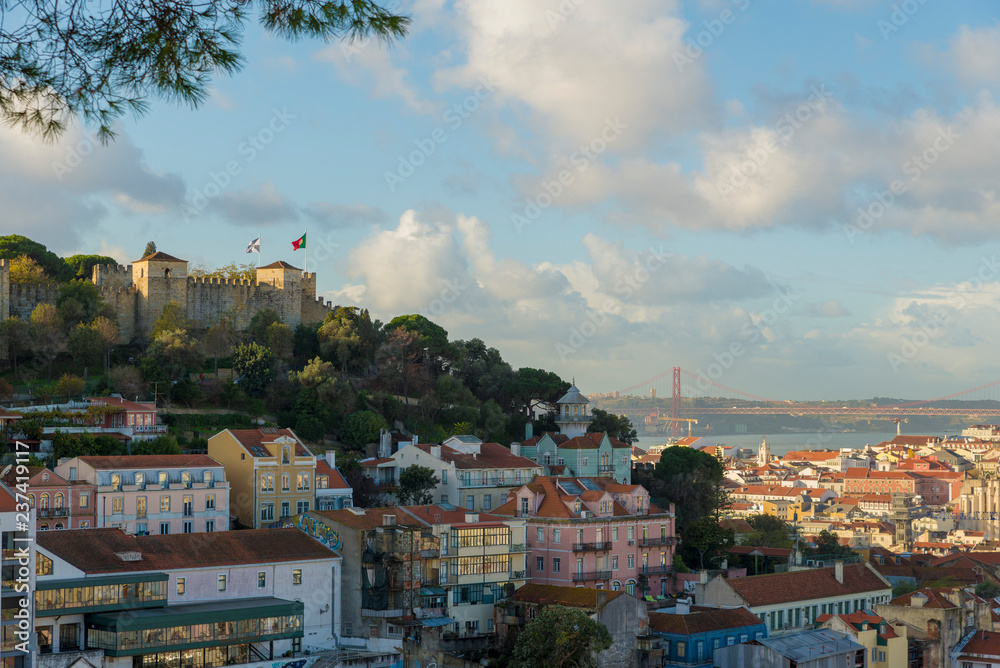 Fototapeta premium Lizbona, Portugalia - 21 listopada 2018: Zamek św. Jerzego i okolice Castelo i Mouraria. w tle most 25 kwietnia na rzece Tag