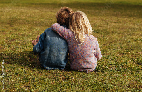 Siblings sitting on the grassy lawn photo