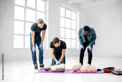 Group of young people practising to make artificial breathing with medical dummies during the first aid training in the white room