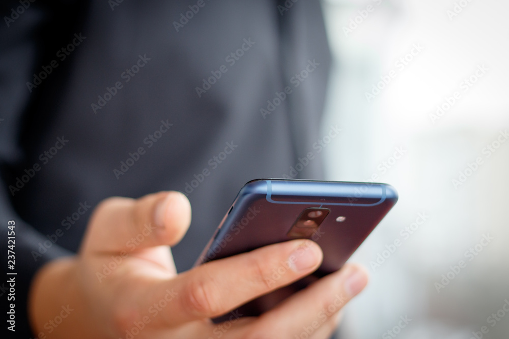 Male hand holding a cell smartphone and writing sms Male hand holding a cell smartphone and writing sms
