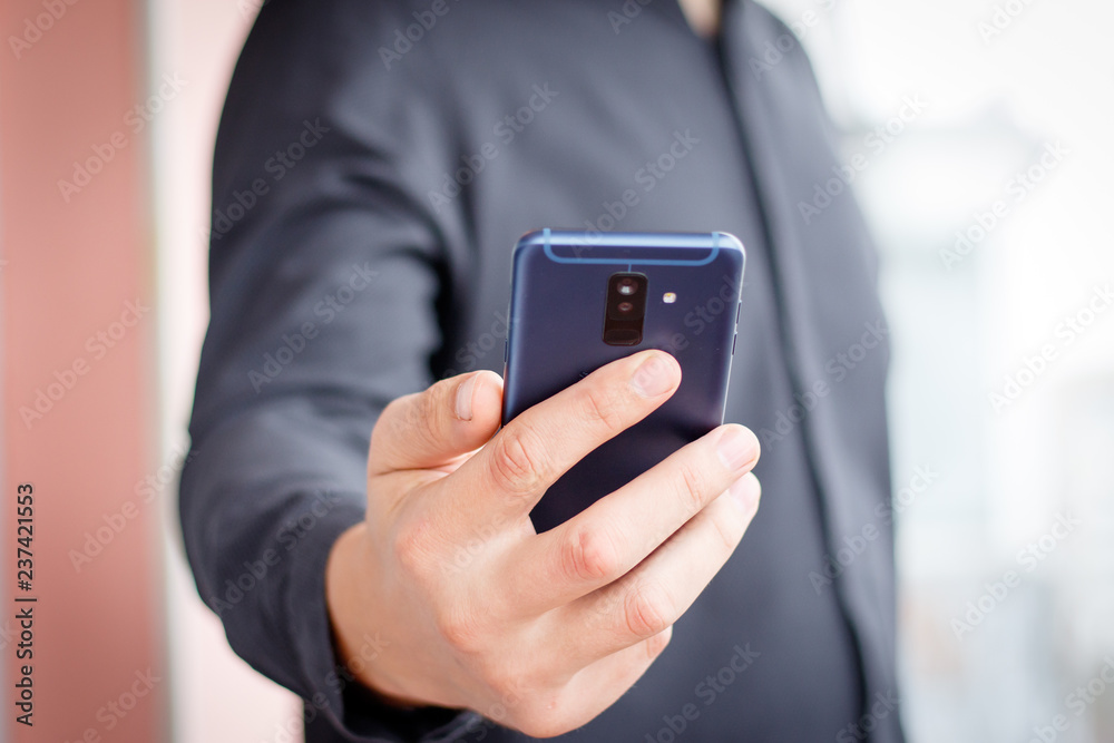 Male hand holding a cell smartphone and writing sms Male hand holding a cell smartphone and writing sms