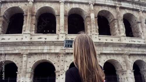 Tourist in Rome. A girl photographs the coliseum on the phone. Italy