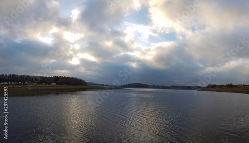 scenic panorama view of sunset under a cloudy sky panorama with sun reflection over water - beautiful scene of a lake while golden sunset / sunrise – sun and clouds reflection over panoramic scenery © klickit24