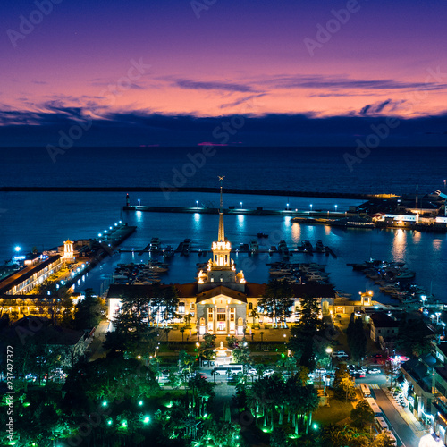Sochi seaport at sunset in the evening. Colorful backlight. Aerial survey. The city resort of Sochi. Stay at the resort. Night walk. City attraction. Yachts and boats in the port.