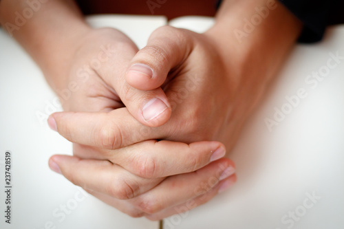 Hands folded in prayer on a Holy Bible in church concept for faith, spirtuality and religion