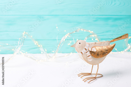 Decorative toy bird and fairy lights on bright wooden  background.