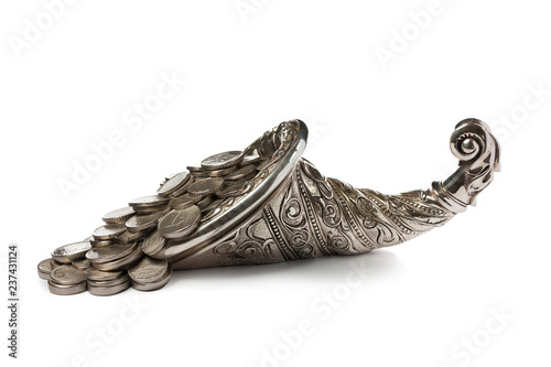 Coins pour out of the silver horn of plenty. Isolated on white background.