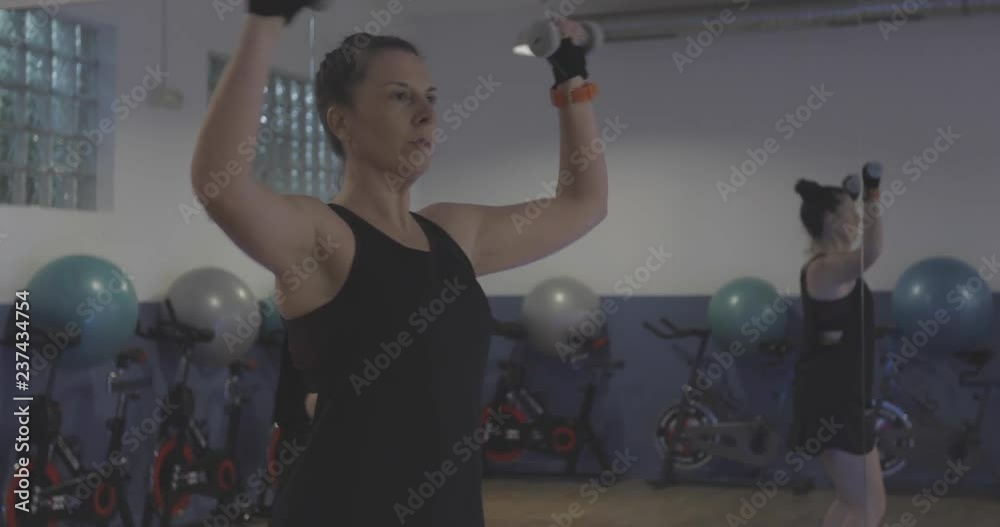 Mujer en gimnasio haciendo deporte con pesas