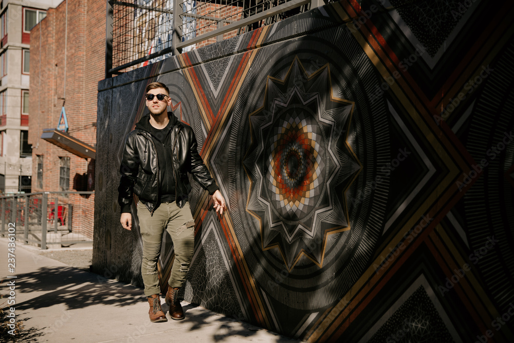 Obraz premium Portrait Headshots of a Young Handsome Attractive Modern Fashion Caucasian Male Guy Modeling near Local Outdoor Art in Urban City in Autumn Winter Season on Bright Sunny Day