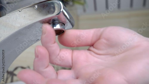 A woman's hand twists the aerator into the faucet in the bathroom.