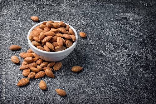 Healthy whole almonds in white bowl on dark concrete
