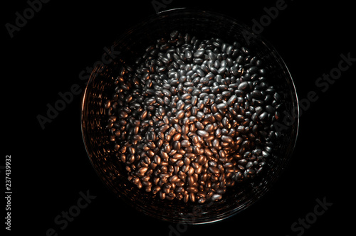 Bowl filled with black beans on a black background