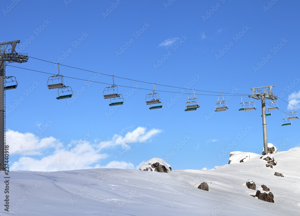 Sunlight chair-lift and blue sky with clouds at ski resort on sun cold evening Sunlight chair-lift and blue sky with clouds at ski resort on sun cold evening