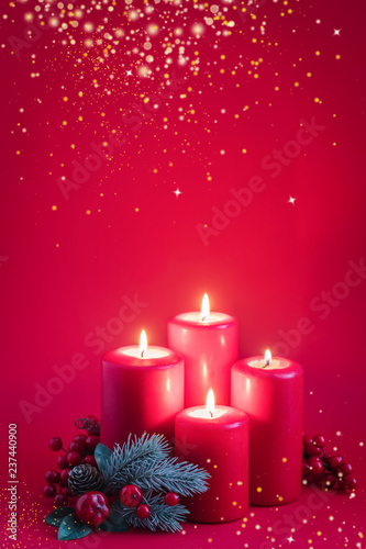 Four red burning advent candles  golden snowflakes and a green spruce branch on a red background