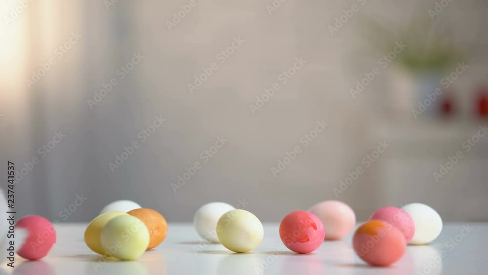 Furry Easter bunny with colored eggs on table, religious holiday greeting, pet
