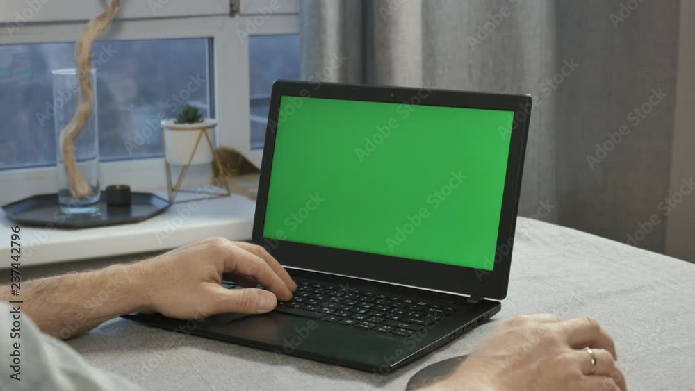 Close-up of male hands that work on a laptop with a green screen. Close-up of male hands that work on a laptop with a green screen.