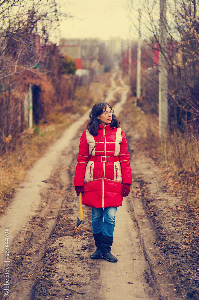 Fototapeta premium strong woman with hatchet standing on a rural road