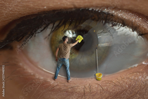 Male worker cleaning the surface of the pupil of the eye with a rag. Concept of healthy eyesight, conjunctivitis and window cleaning. photo