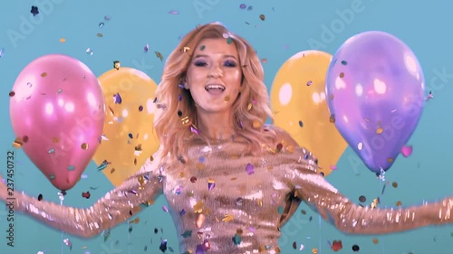 woman dancing at a party in a beautiful shiny dress. With balloons and confitti
