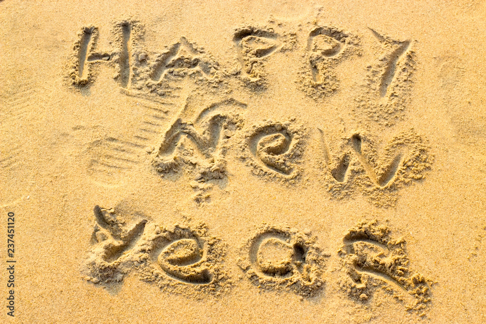 Fototapeta premium Hand inscription Happy New Year on the sand. 