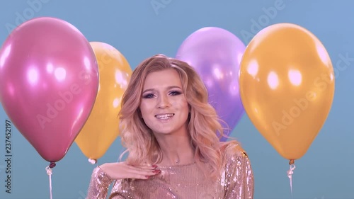 Young girl posing for the camera. Next to her balloons.