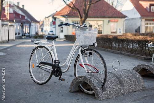White step-through frame bicycle parked with antitheft system on city streets