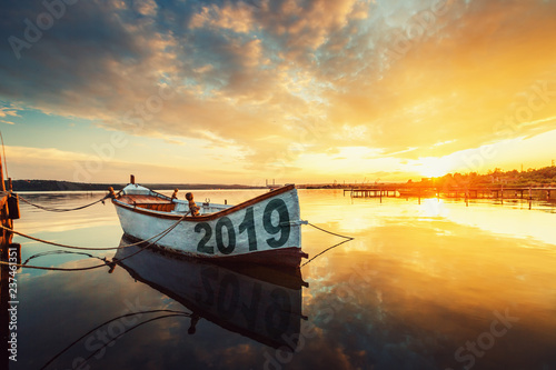 Happy New Year 2019 concept, lettering on the Boat with a reflection in the water at sunset