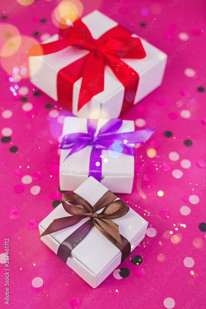 Three gift boxes with colorful ribbons on pink background with confetti. Three gift boxes with colorful ribbons on pink background with confetti.