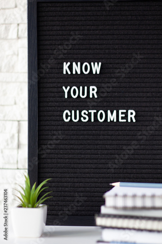 Know Your Customer - business concept, white text message on black board, stack of notebooks