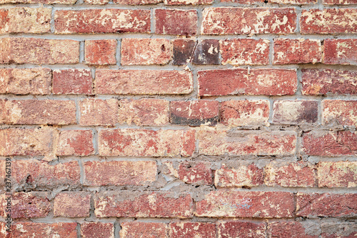 Background of red vintage brick wall, surface close-up. Colorful grunge texture of wall with peeling plaster, copy space