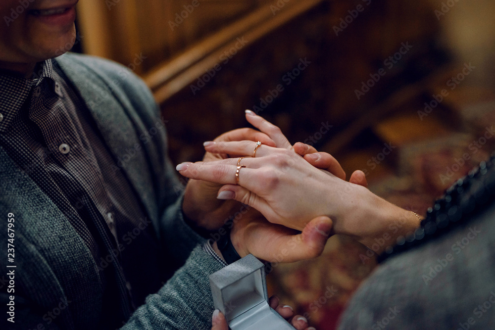 Close up man put on the engagement ring on womans hand. Man proposing to his girlfriend.