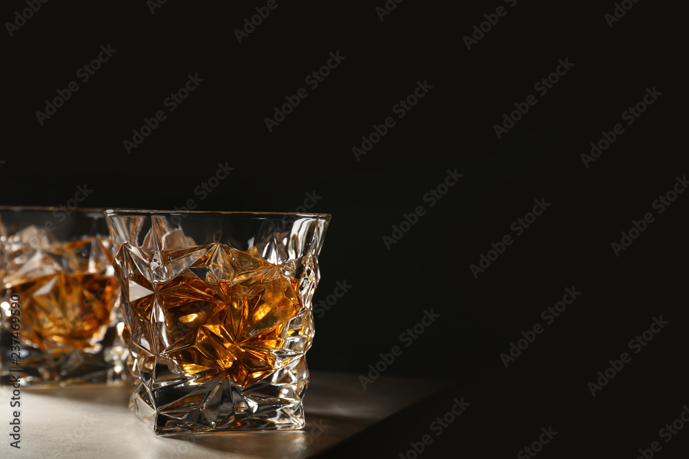 Golden whiskey in glass with ice cubes on table. Space for text Golden whiskey in glass with ice cubes on table. Space for text