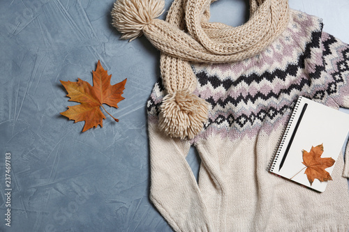 Flat lay composition with warm sweater and scarf on color background
