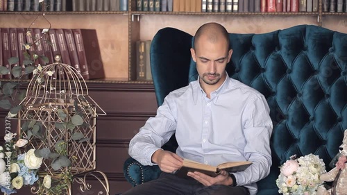 a man sitting in a chair in his library reading a book