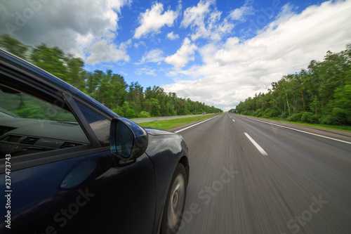 The car moves at high speed on highway at the sunny summer day.