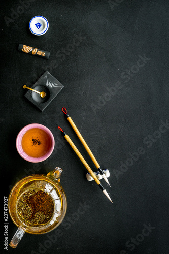 Chinese or japanese traditions. Calligraphy and tea ceremony concept. Special writting pen, ink near teapot and cup of tea, insense on black background top view copy space
