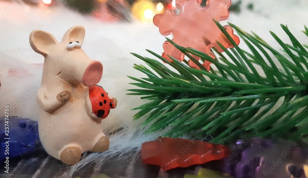Toy pig and winter decor, congratulations on the holiday. Symbol of the year of the pig on the background of Christmas lights