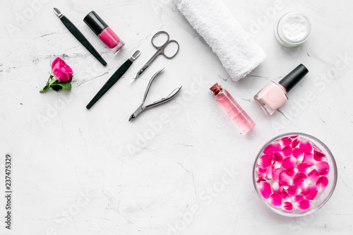 tools for manicure with spa salt and rose on white stone background top view space for text