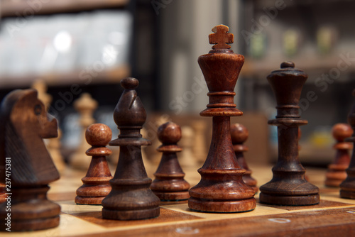 Wooden chess figures. Closeup on chess board and dark figures. Handmade old chess.