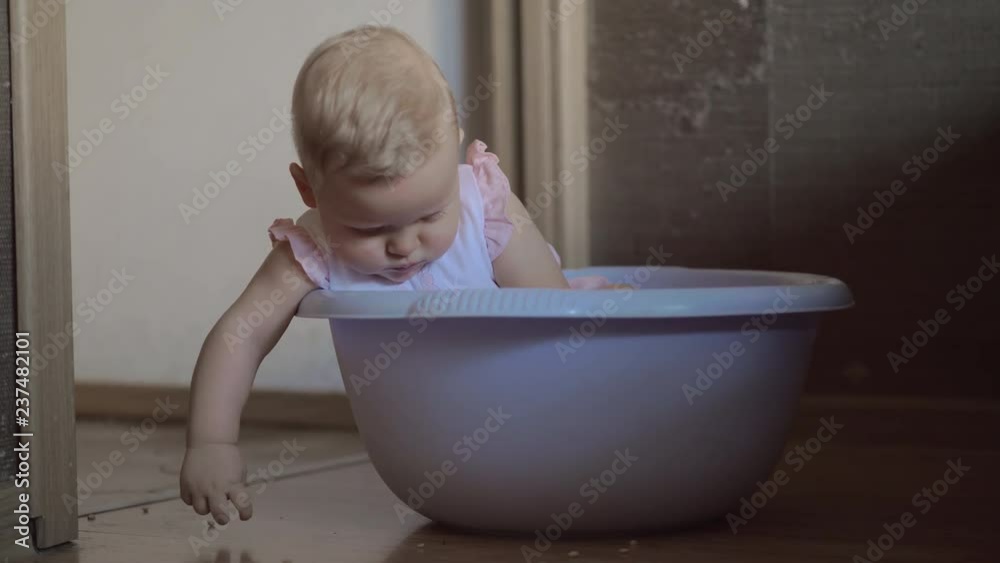 Medium shot of a cute baby girl in a round blue tub full of lentils playing in her nursery at home 2 Medium shot of a cute baby girl in a round blue tub full of lentils playing in her nursery at home 2